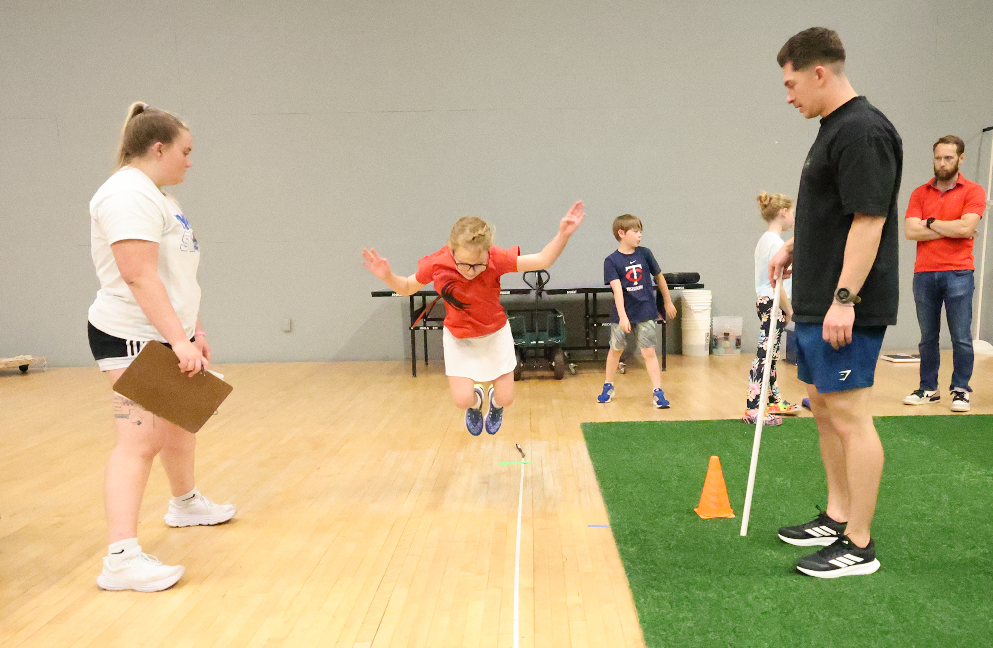 A young athlete jumps over measurement tools.