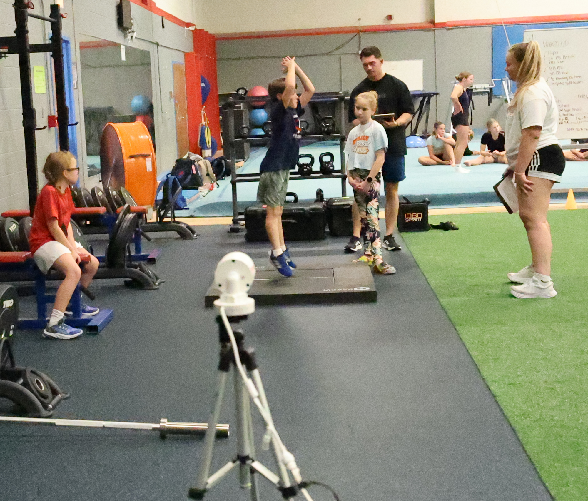 A young athlete and a sideline scout work at sport performance measuring devices.